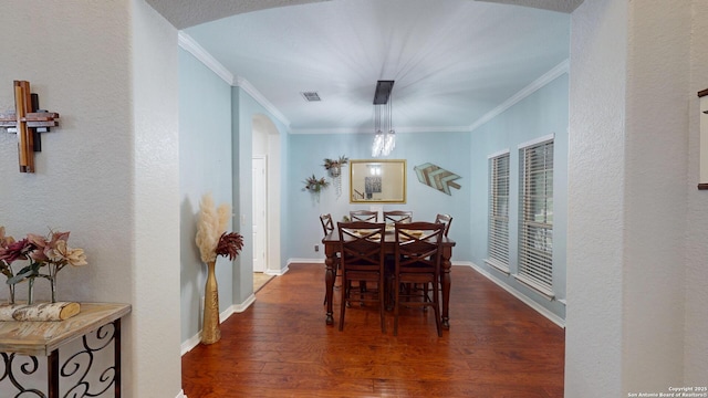 dining area featuring baseboards, crown molding, wood finished floors, and visible vents