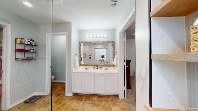 full bath featuring visible vents, a sink, a textured ceiling, and toilet