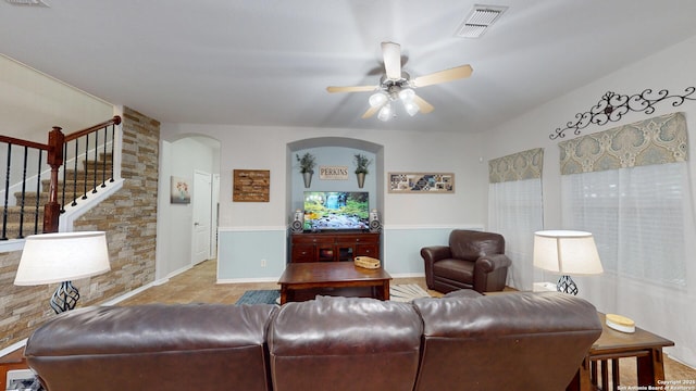 living room with stairway, ceiling fan, arched walkways, baseboards, and visible vents