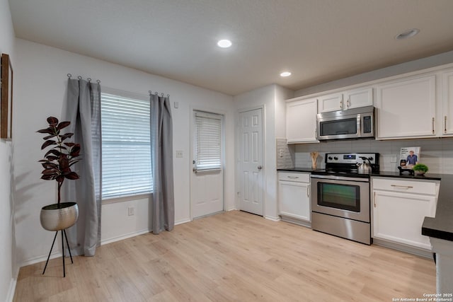8934 Oakwood, San Antonio, TX 78254 - kitchen featuring stainless steel appliances, dark countertops, light wood-type flooring, baseboards, and white cabinetry