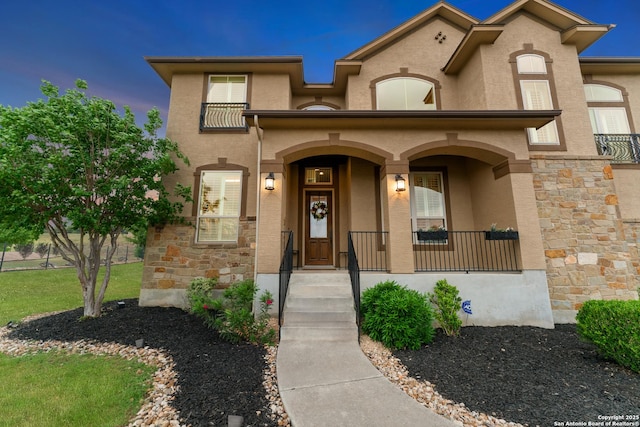 mediterranean / spanish home with stucco siding, a porch, and stone siding