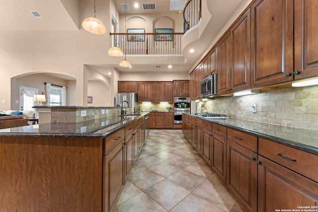 kitchen featuring appliances with stainless steel finishes, a sink, visible vents, and a high ceiling