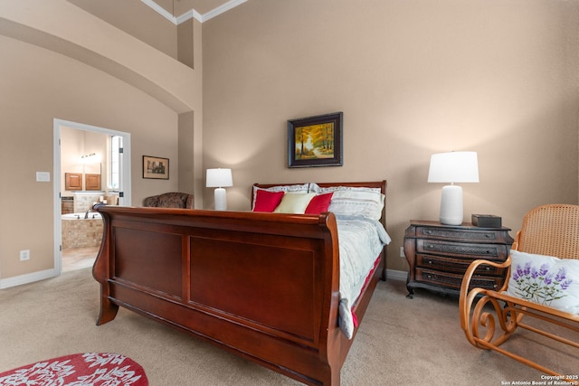 carpeted bedroom with crown molding, arched walkways, ensuite bath, and baseboards