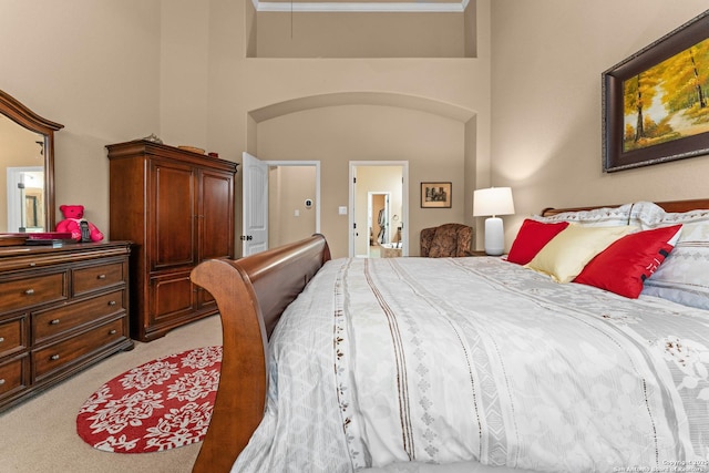 bedroom featuring attic access, a high ceiling, and light carpet