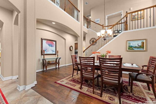 dining space featuring a high ceiling, stairway, visible vents, baseboards, and arched walkways