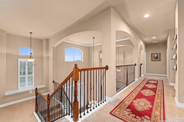 hallway featuring an upstairs landing, arched walkways, carpet floors, baseboards, and recessed lighting