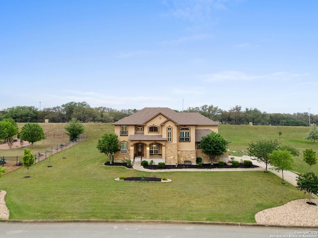 view of front facade with fence, stone siding, covered porch, a front yard, and stucco siding
