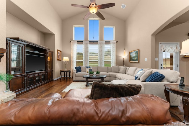 living area featuring arched walkways, wood finished floors, ceiling fan, visible vents, and high vaulted ceiling