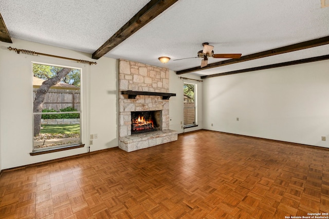 unfurnished living room with ceiling fan, a textured ceiling, beamed ceiling, and plenty of natural light