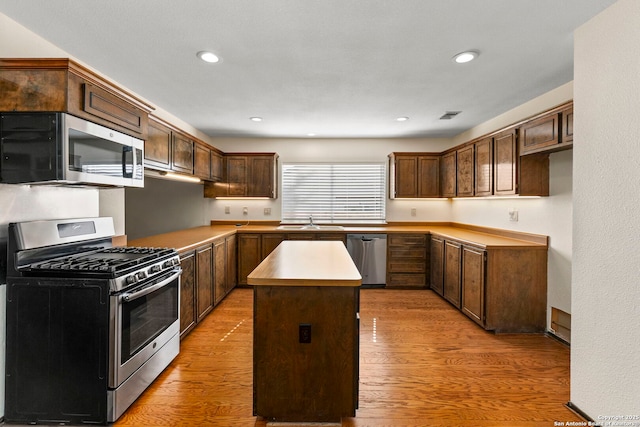 kitchen with a center island, a sink, stainless steel appliances, light wood-style flooring, and visible vents