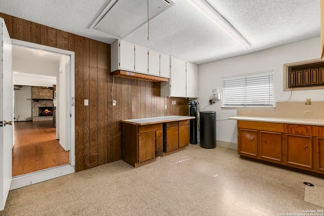 kitchen featuring brown cabinetry, light countertops, a textured ceiling, and a fireplace