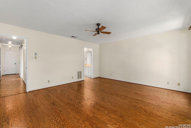 spare room with attic access, ceiling fan, wood finished floors, and visible vents