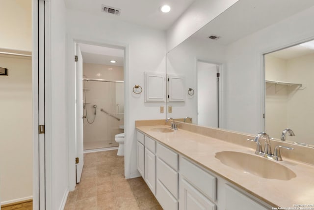 bathroom with visible vents, a sink, a shower stall, and toilet