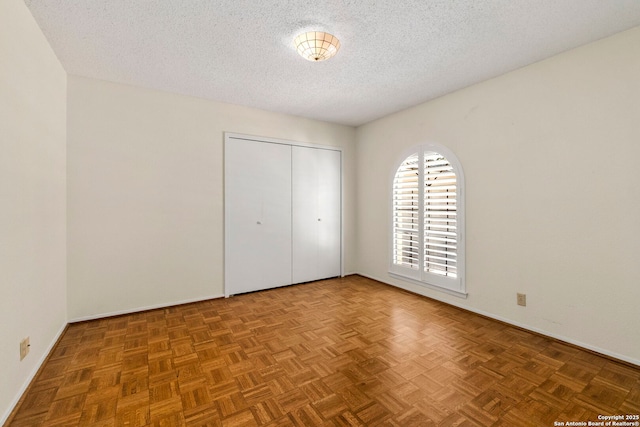 unfurnished bedroom featuring baseboards, a textured ceiling, and a closet