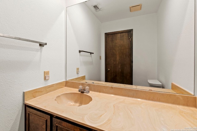 bathroom with visible vents, vanity, and toilet