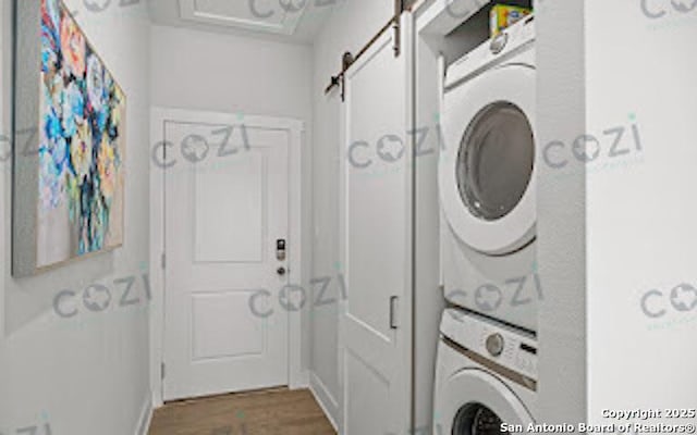 930 S Eagle St Unit 104, Fredericksburg, TX 78624 - clothes washing area featuring a barn door, wood finished floors, baseboards, stacked washer and dryer, and laundry area