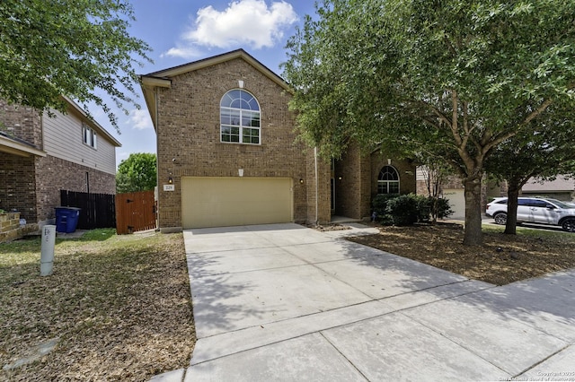 traditional-style house featuring brick siding, an attached garage, fence, and driveway