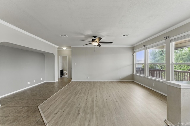 spare room with ornamental molding, baseboards, a ceiling fan, and visible vents