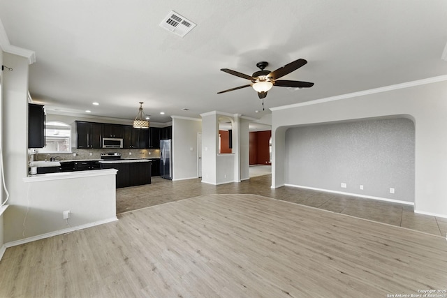 unfurnished living room featuring light wood-type flooring, ornamental molding, visible vents, and ceiling fan