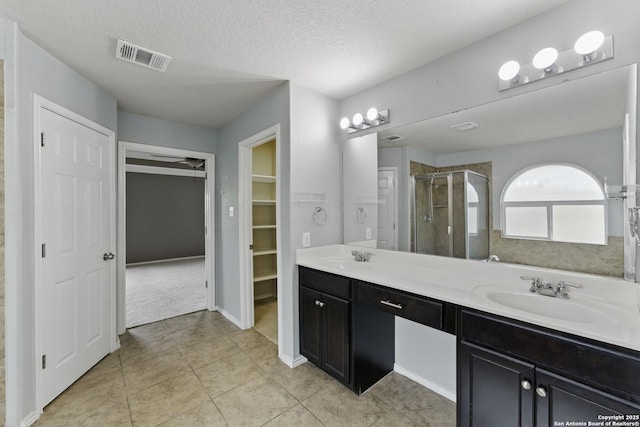 bathroom with double vanity, visible vents, a stall shower, and a sink