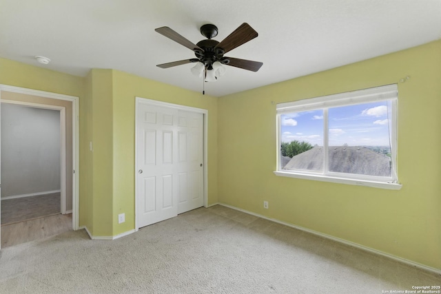 unfurnished bedroom featuring baseboards, a ceiling fan, carpet flooring, and a closet
