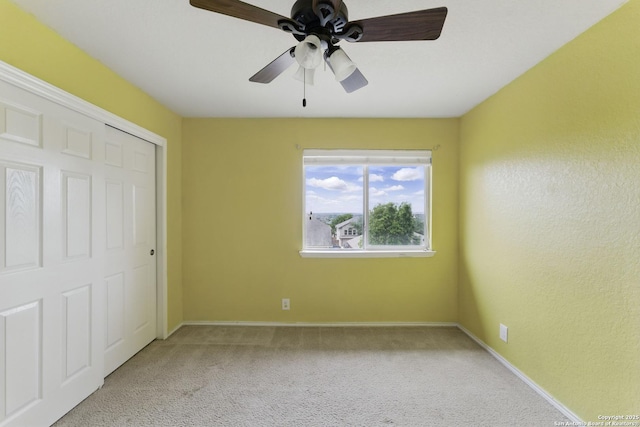 unfurnished bedroom with light carpet, baseboards, a closet, and ceiling fan