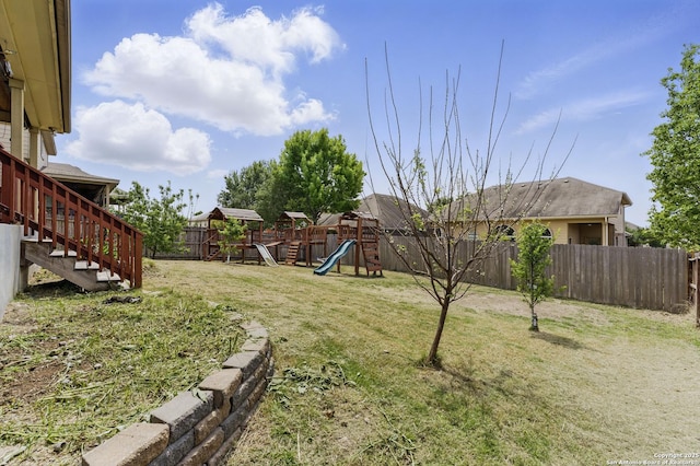 view of yard featuring a fenced backyard, a playground, and stairway