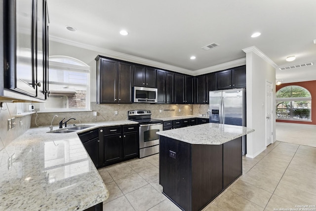 kitchen with stainless steel appliances, visible vents, ornamental molding, a sink, and light stone countertops