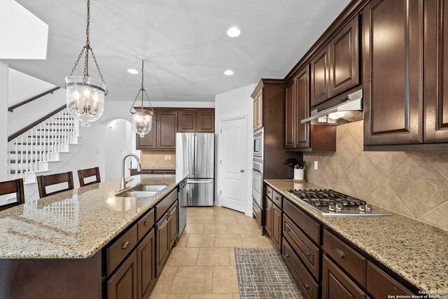 kitchen with recessed lighting, under cabinet range hood, dark brown cabinets, a sink, and appliances with stainless steel finishes