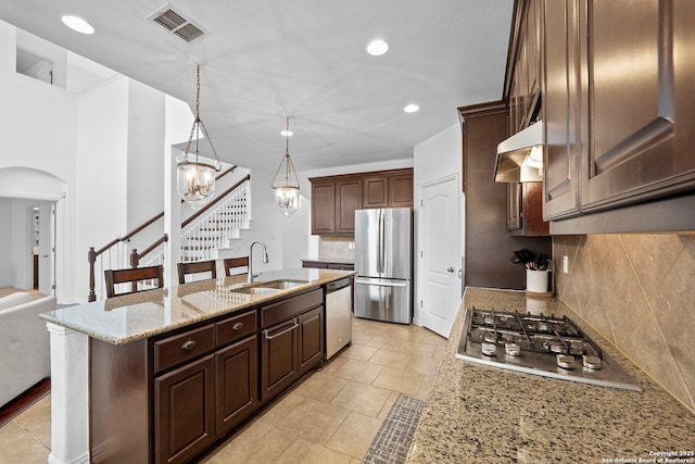 kitchen featuring a sink, stainless steel appliances, backsplash, under cabinet range hood, and visible vents