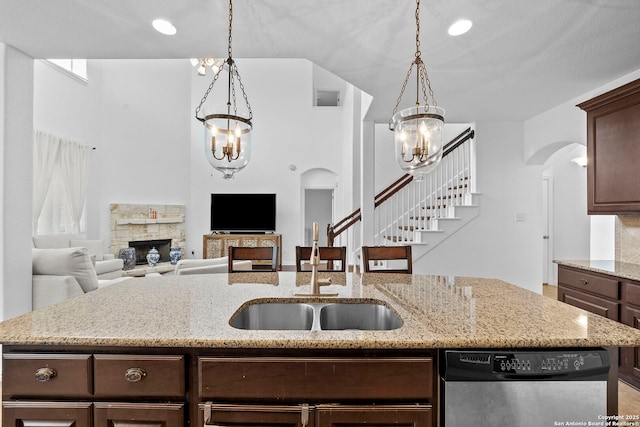 kitchen featuring arched walkways, visible vents, a chandelier, dishwasher, and a fireplace