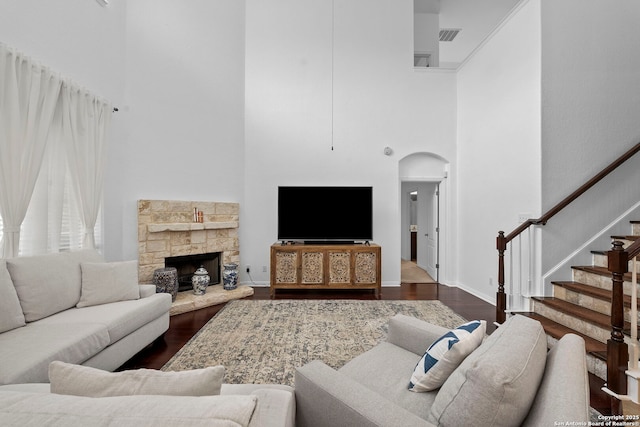 living room featuring arched walkways, a high ceiling, dark wood-type flooring, and stairs
