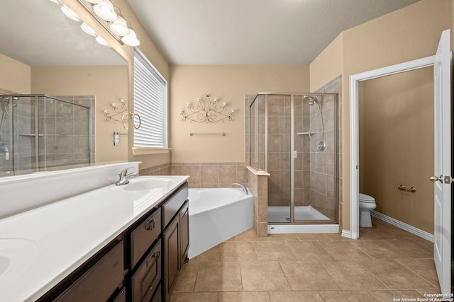 bathroom featuring a sink, double vanity, toilet, a stall shower, and a garden tub
