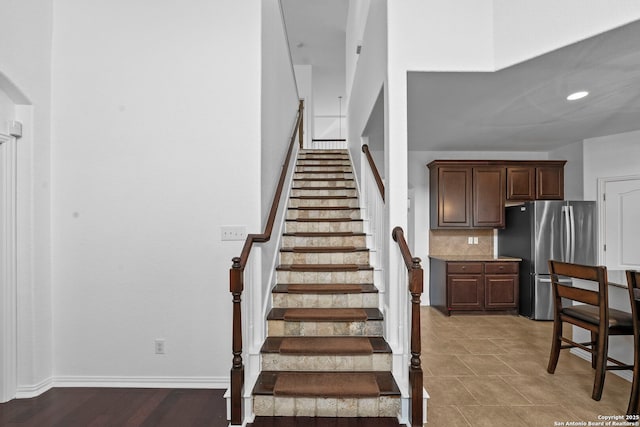 staircase with recessed lighting, arched walkways, and baseboards