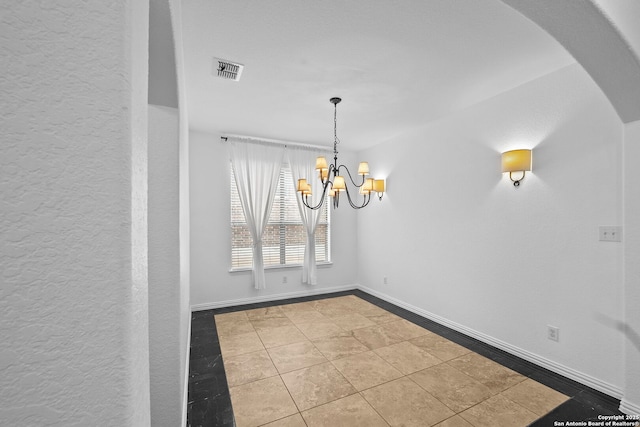 unfurnished dining area with tile patterned floors, arched walkways, a textured wall, a notable chandelier, and visible vents