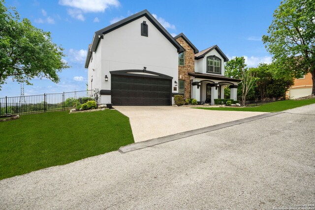 french country style house with stucco siding, concrete driveway, a front lawn, and fence
