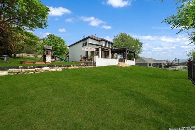 back of house featuring a yard, a trampoline, and a playground