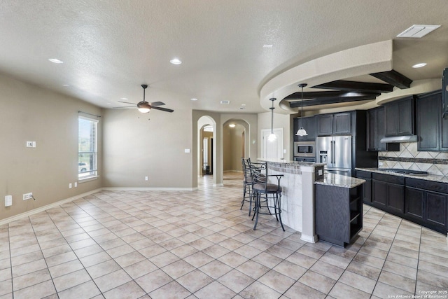 kitchen featuring stainless steel appliances, arched walkways, a textured ceiling, recessed lighting, and ceiling fan