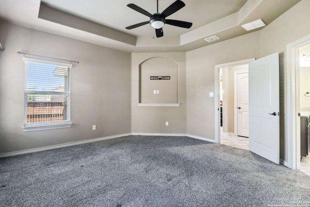 carpeted empty room with baseboards, a ceiling fan, visible vents, and a raised ceiling