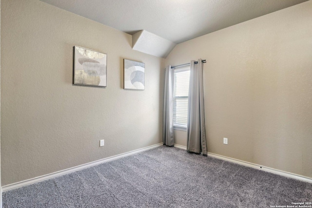 carpeted spare room with lofted ceiling and baseboards
