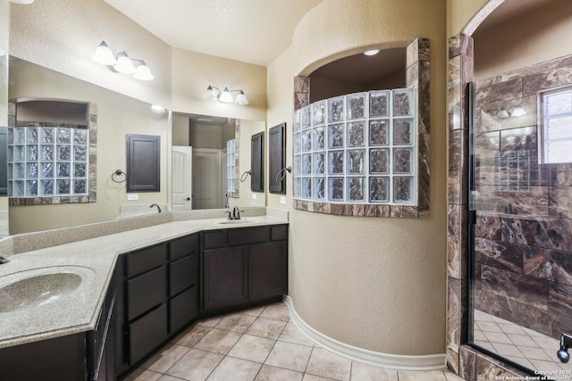full bath featuring a textured wall, a sink, double vanity, and a tile shower