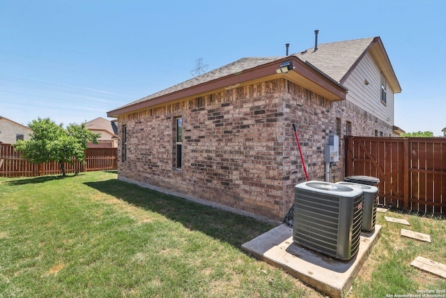 exterior space featuring a lawn, central AC unit, brick siding, and a fenced backyard