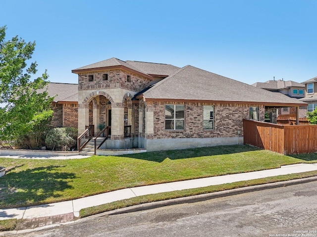 view of front of property with fence, a front lawn, brick siding, and roof with shingles