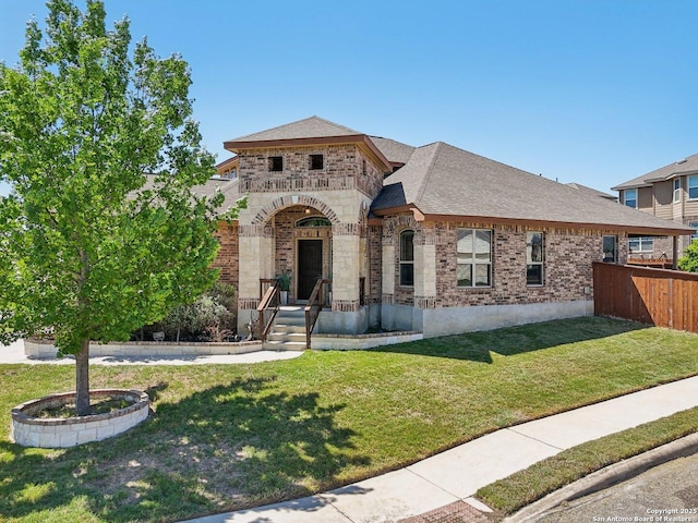 view of front of property with fence, a front lawn, brick siding, and roof with shingles