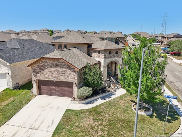 french country style house featuring an attached garage, brick siding, a residential view, and a front yard