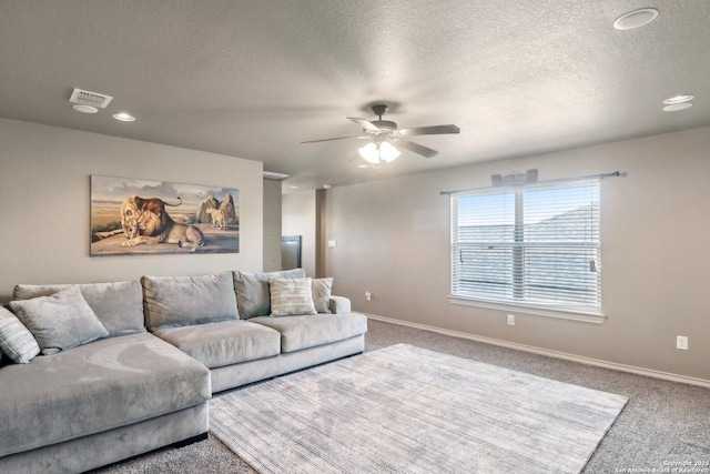 carpeted living area featuring a textured ceiling, visible vents, a ceiling fan, and baseboards