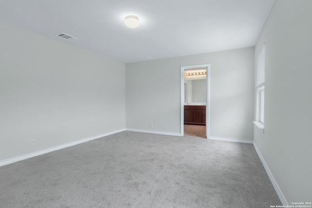 unfurnished bedroom with carpet floors, ensuite bathroom, visible vents, and baseboards