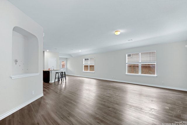 unfurnished living room featuring baseboards, dark wood-type flooring, visible vents, and a sink