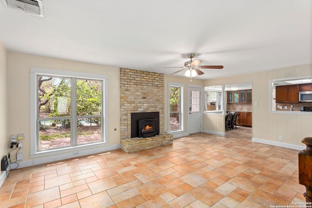 unfurnished living room featuring baseboards, a ceiling fan, stone finish floor, and visible vents