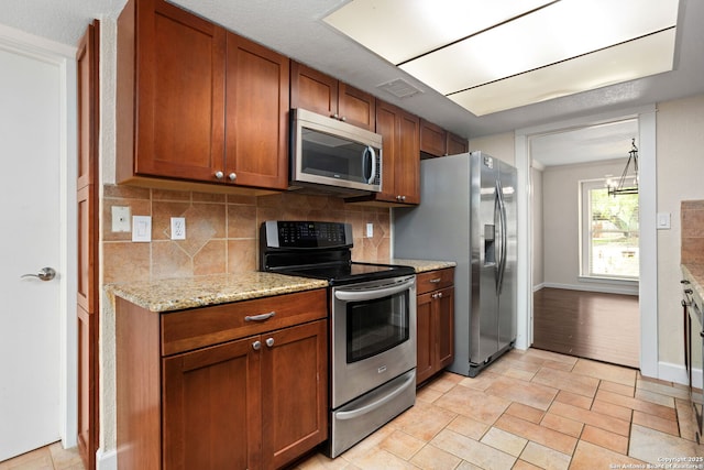 kitchen with brown cabinetry, visible vents, backsplash, and appliances with stainless steel finishes